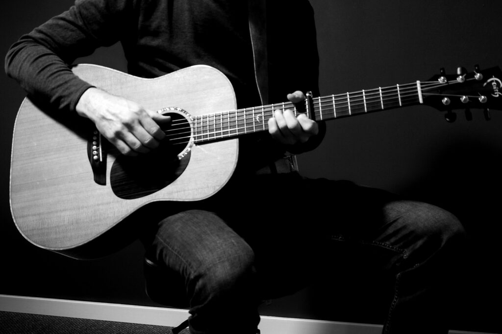 Handgemachte Musik – Gitarrist spielt Akustikgitarre in stilvoller Schwarz-Weiß-Optik. Livemusik in Augsburg und Umgebung.
